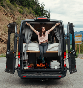 a lady sitting on the back edge of a karma camper van