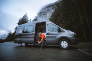 Male putting on hiking shoes on step on Karma Campervan