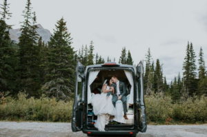 a married couple sitting in the back of a camper van