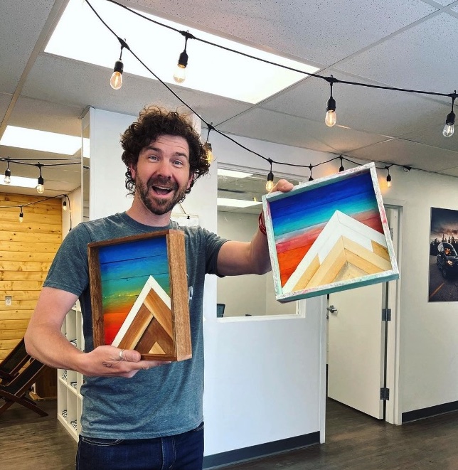 Dave holding 2 pieces of artwork from Western Canadian artist
